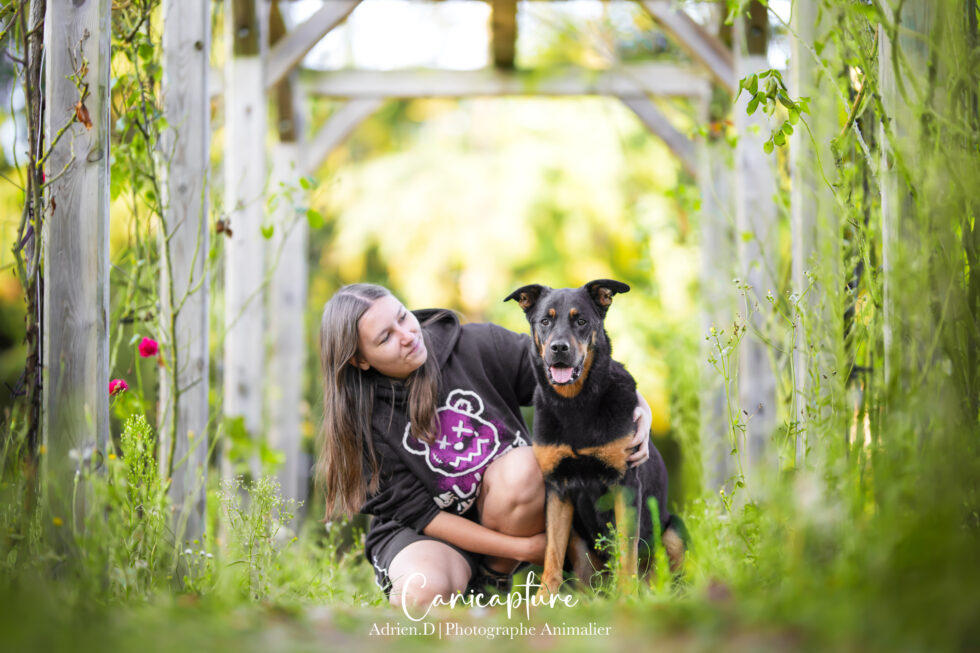 Lucie et Maxou, capturés dans un moment complice sous une pergola verdoyante par Adrien Dupic, photographe animalier et familial.